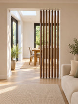 Lyndhurst wooden swivel room divider with slim brown slats and pressure-fit fittings in a bright Scandinavian living room.