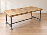 Robin reclaimed wood desk with scaffold-pipe legs and a thick framed tabletop in a bright Scandinavian room.