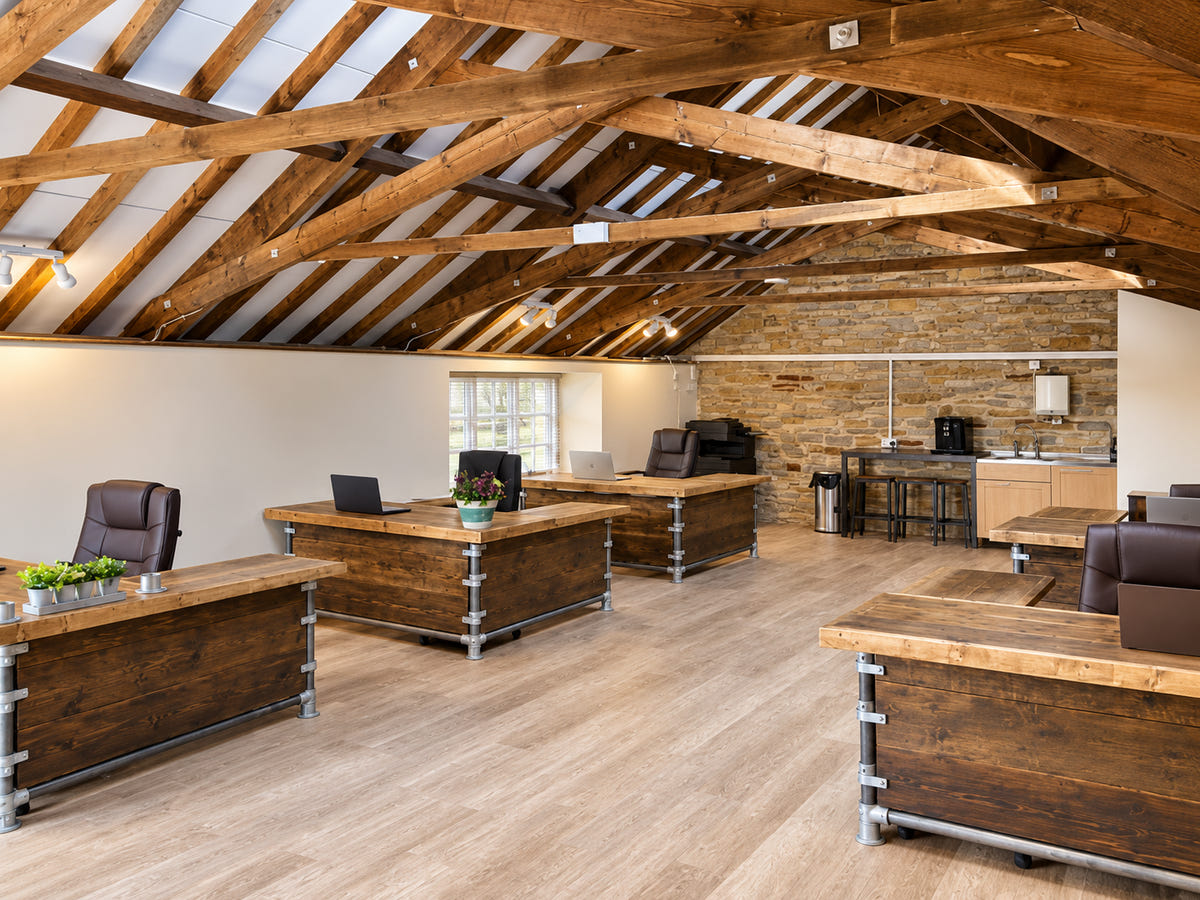 Industrial reclaimed timber office desks beneath exposed beams