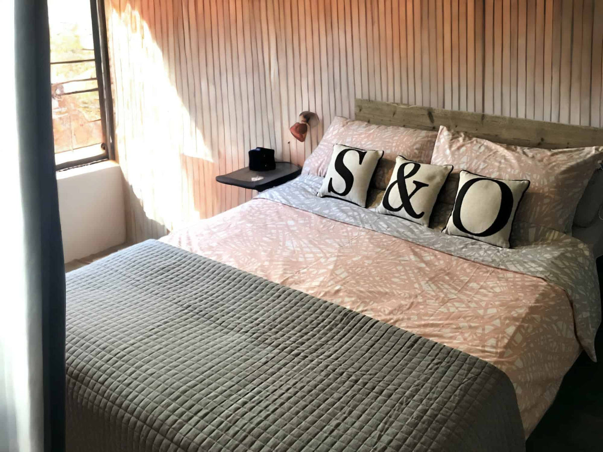 Rustic industrial bed with a reclaimed-wood headboard, photographed from the side.