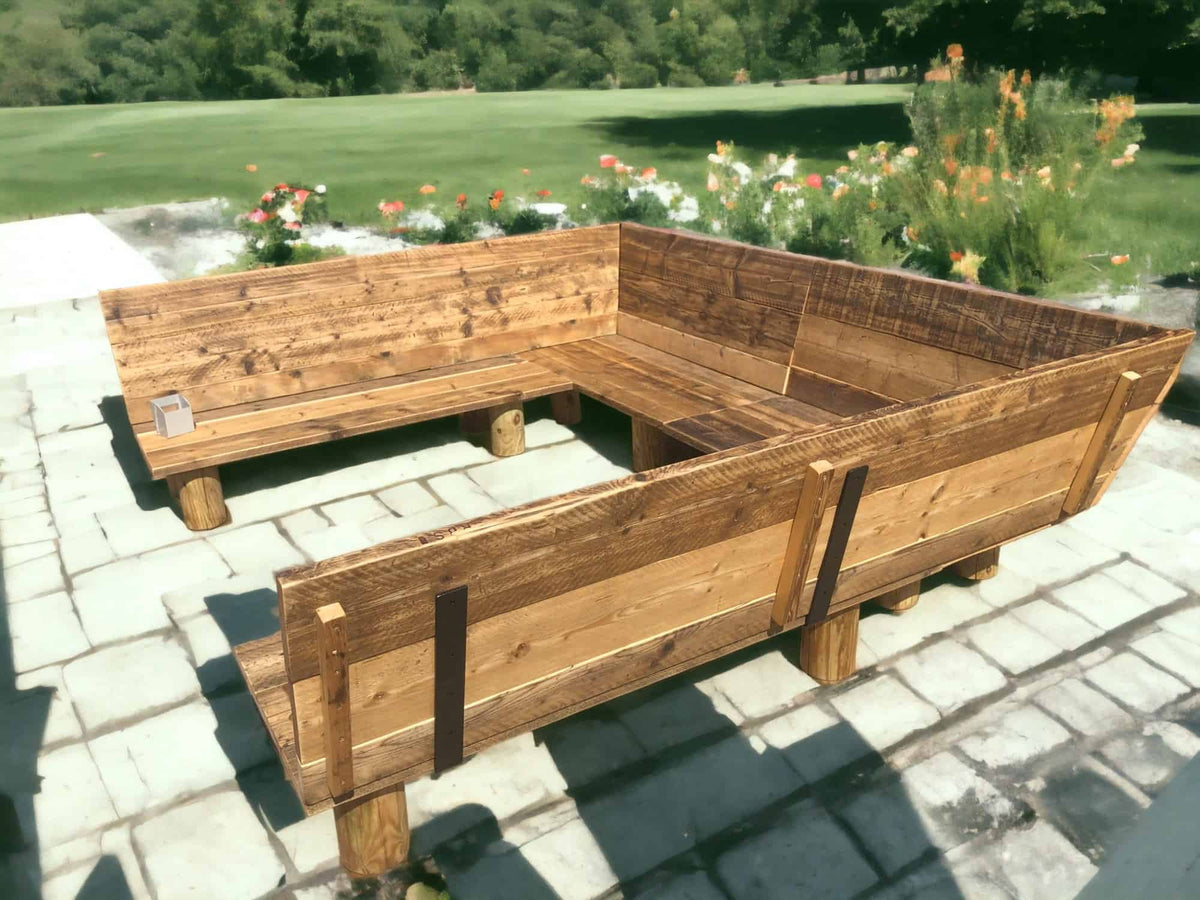 U-shaped outdoor timber garden bench on a paved terrace.