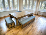 Reclaimed-wood dining and gaming table with three upholstered storage benches in a bright room.