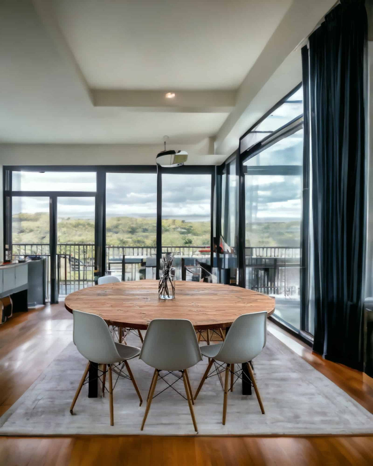 Circular wooden dining table in a modern glazed dining room.