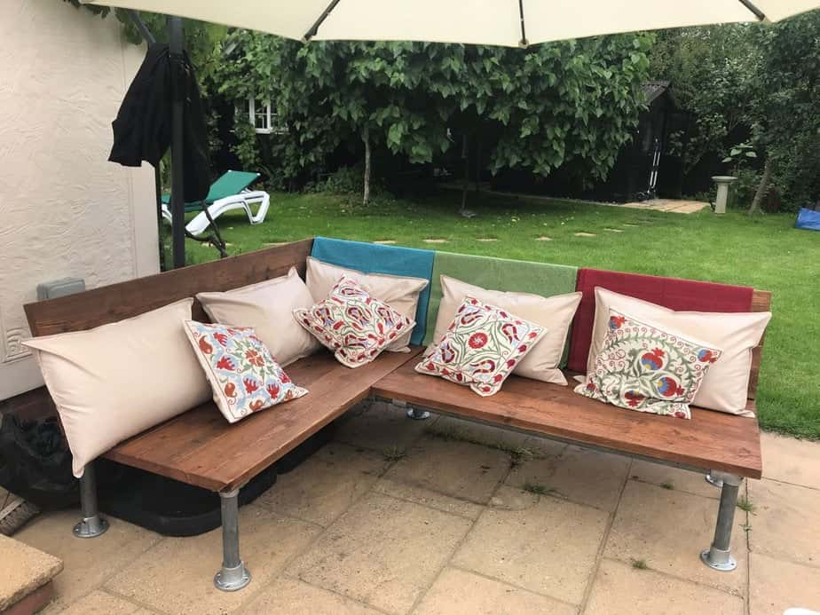 Outdoor L-shaped timber corner bench with cushions.