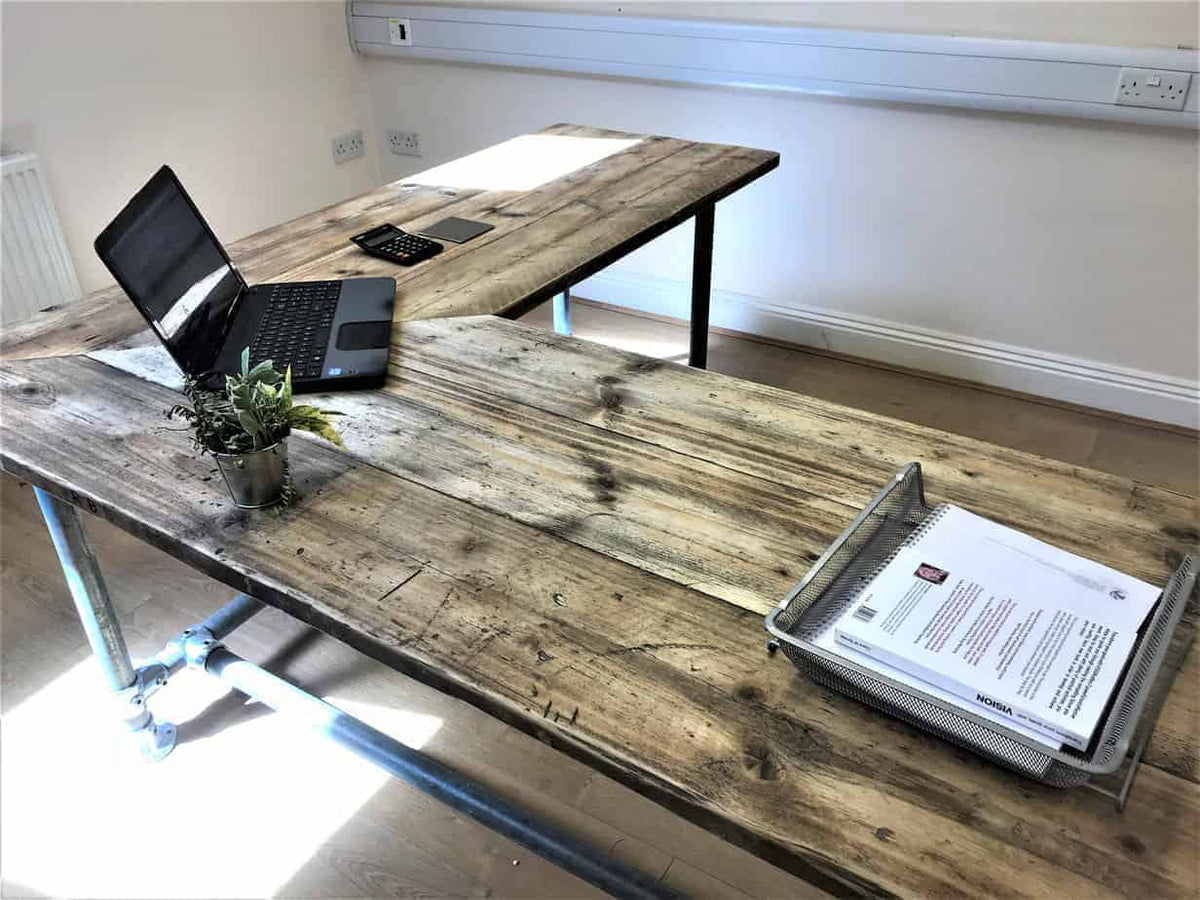 L-shaped reclaimed wood corner desk set up with laptops.