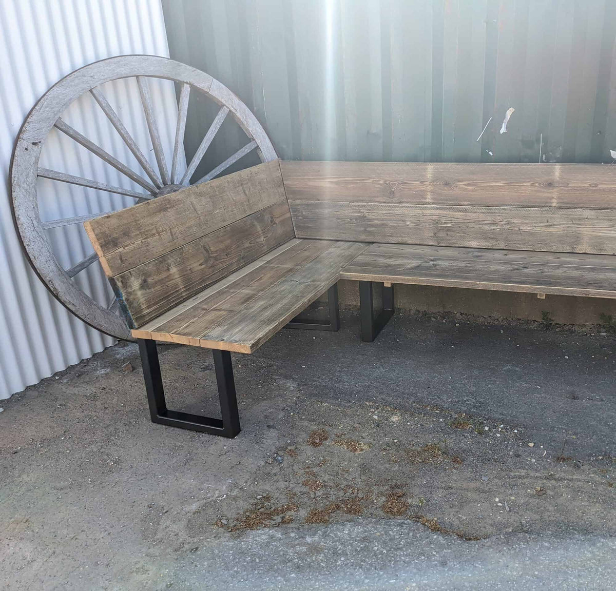 Reclaimed wood box-leg corner bench in a workshop.