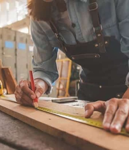 Carpenter measuring a piece of wood in the workshop