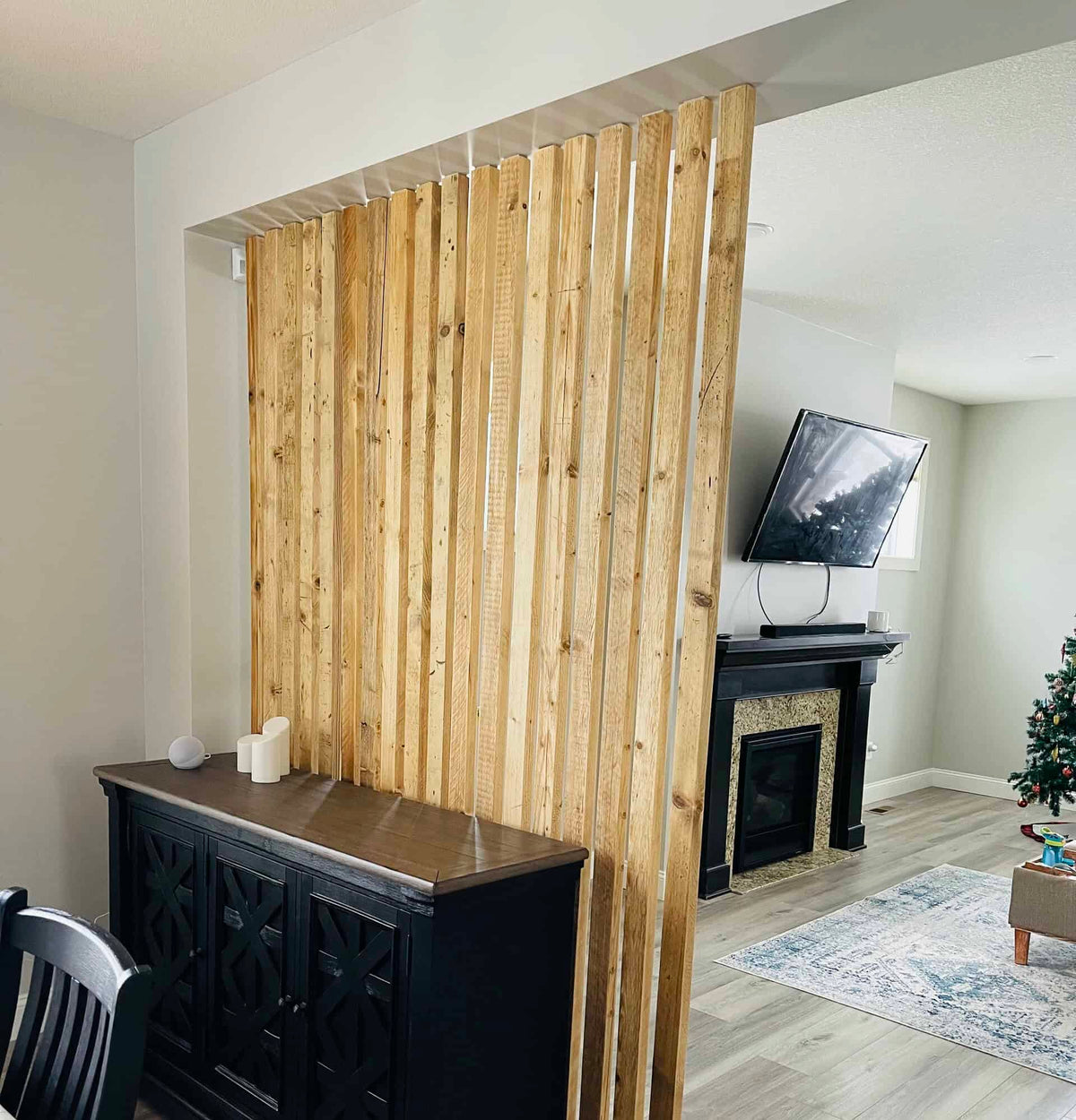 Full-height reclaimed-wood slat divider separating a dining area from a living room.