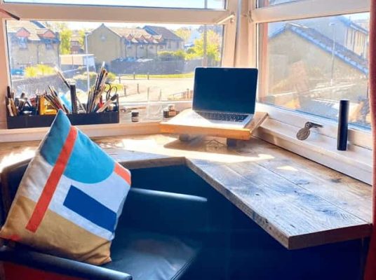 Laptop and seating beside a reclaimed-wood desk in the Robert Rose Carpentry office