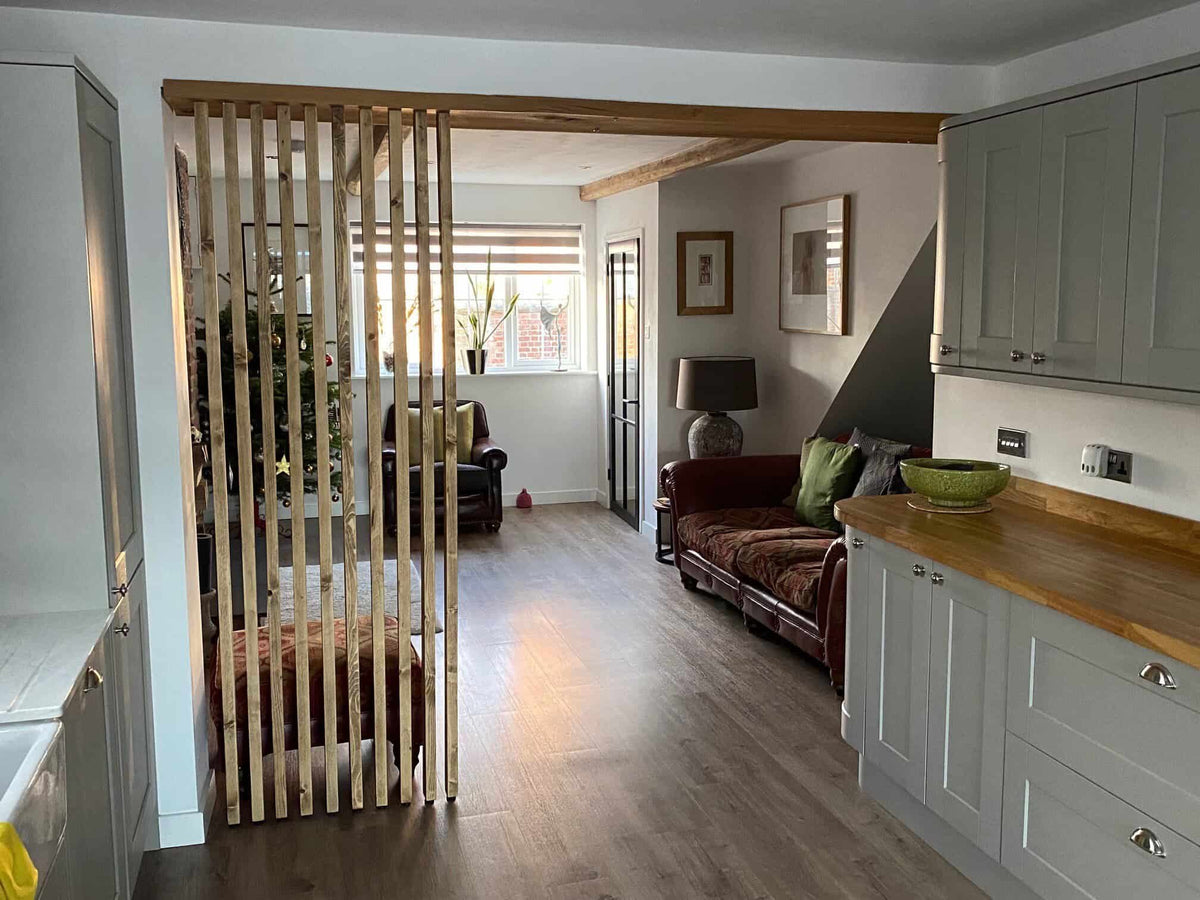 Floor-to-ceiling natural-wood slat divider between a kitchen and living area.