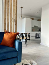 Natural-wood slat room divider beside a blue sofa in an open-plan living and dining space.