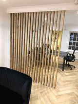 Floor-to-ceiling natural-wood slat divider separating a living area from a home office.
