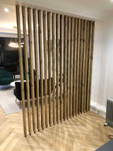 Floor-to-ceiling reclaimed-wood slat divider separating a modern seating area.