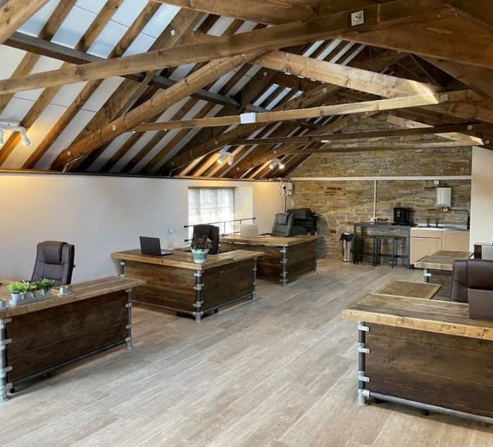 Industrial reclaimed-wood desks in a warm timber-framed office